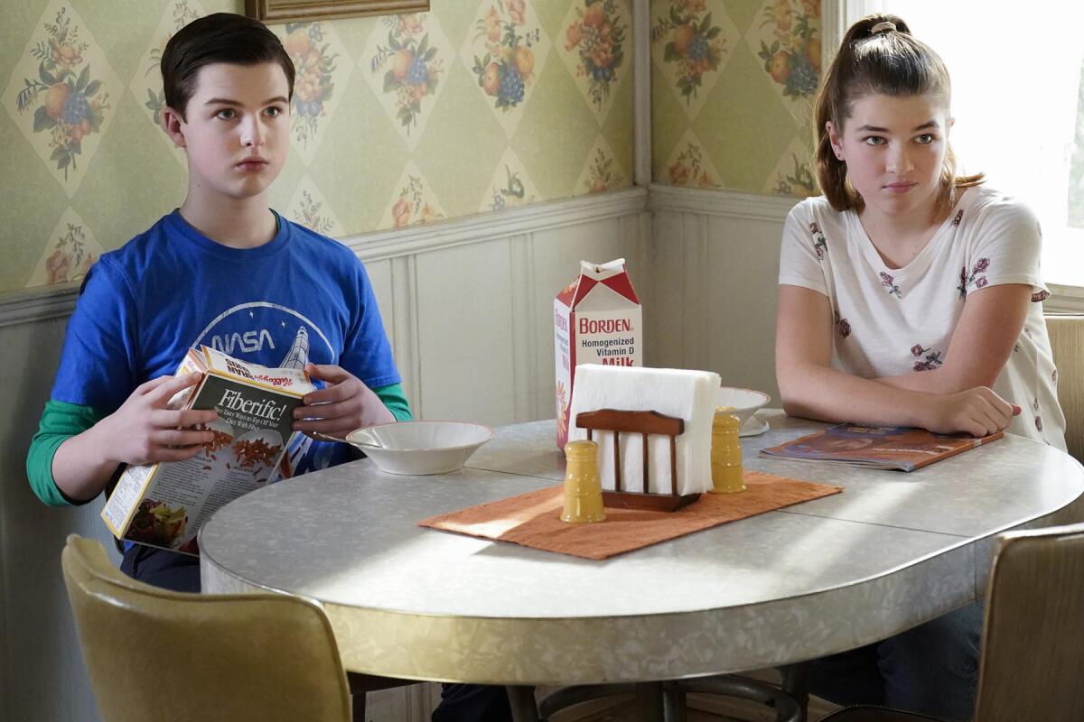Iain Armitage and Raegan Revord sitting at a kitchen table in "Young Sheldon" on CBS.