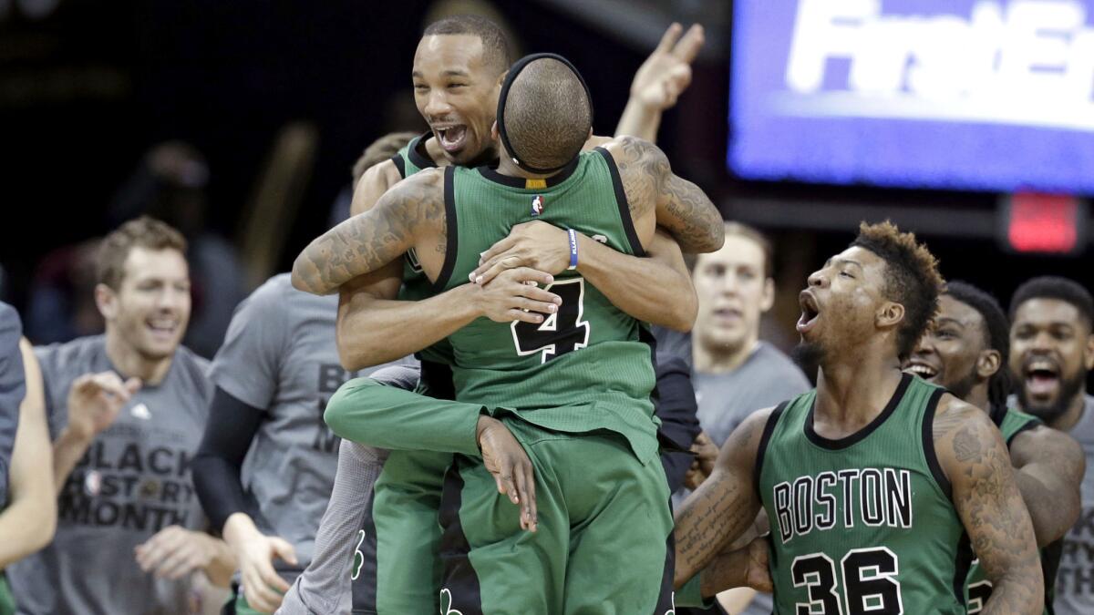 Celtics guard Avery Bradley is swarmed by teammates, including Isaiah Thomas (4) after making a game-winning three-pointer against the Cavaliers on Friday night.
