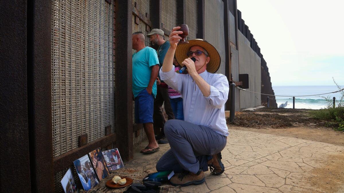 Pastor John Fanestil from the First United Methodist Church in San Diego prepares to offer communion to those on the north side of the border fence.