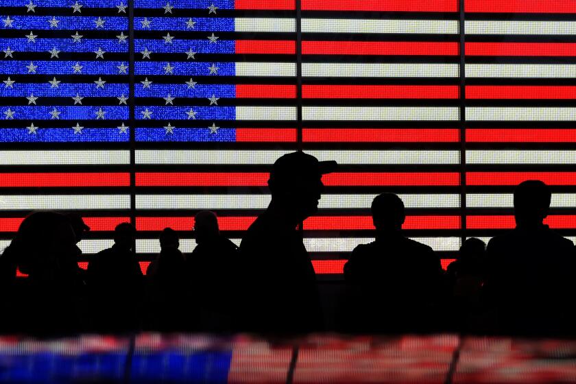 ARCHIVO - Varias personas se congregan frente a unas pantallas que muestran la bandera estadounidense en Times Square, Nueva York, el 9 de agosto de 2024. (AP Foto/Pamela Smith, Archivo)