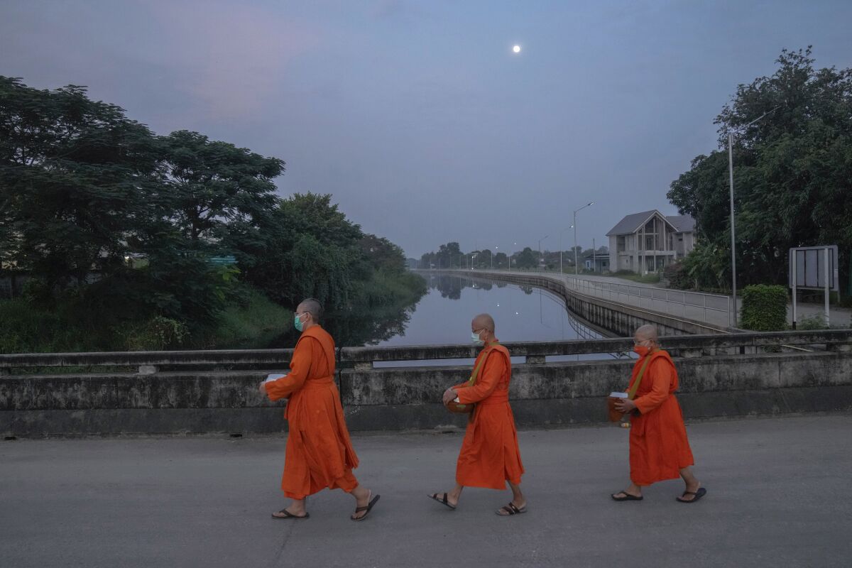 From left, Bhikkhuni Dhammavanna, Bhikkhuni Dhammaparipunna and Bhikkhuni Dhammasumana walk to collect alms from devotees in Nakhon Pathom province on Sunday, Nov. 21, 2021. Women are banned from becoming monks in Thailand, where over 90% of the population is Buddhist. Historically, women could only become white-cloaked nuns often treated as glorified temple housekeepers. But dozens have traveled to Sri Lanka to receive full ordination. (AP Photo/Sakchai Lalit)