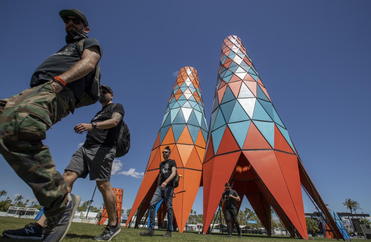 Coachellal goers walk past Francis Kéré's "Sarbale ke" set of towers during the opening day of the three day event.