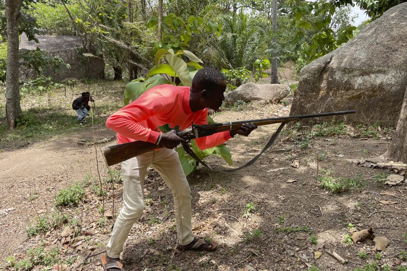 Joshua Danjuma, 36, poses with a handcrafted riffle in Kunji Village, Southern Kaduna Nigeria, Thursday , April 27, 2023. Danjuma, a hunter who lost two of his five children in a late night March 2023 gunmen attack that left 33 people dead, has joined others in protecting their homes. (AP Photo/Chinedu Asadu)