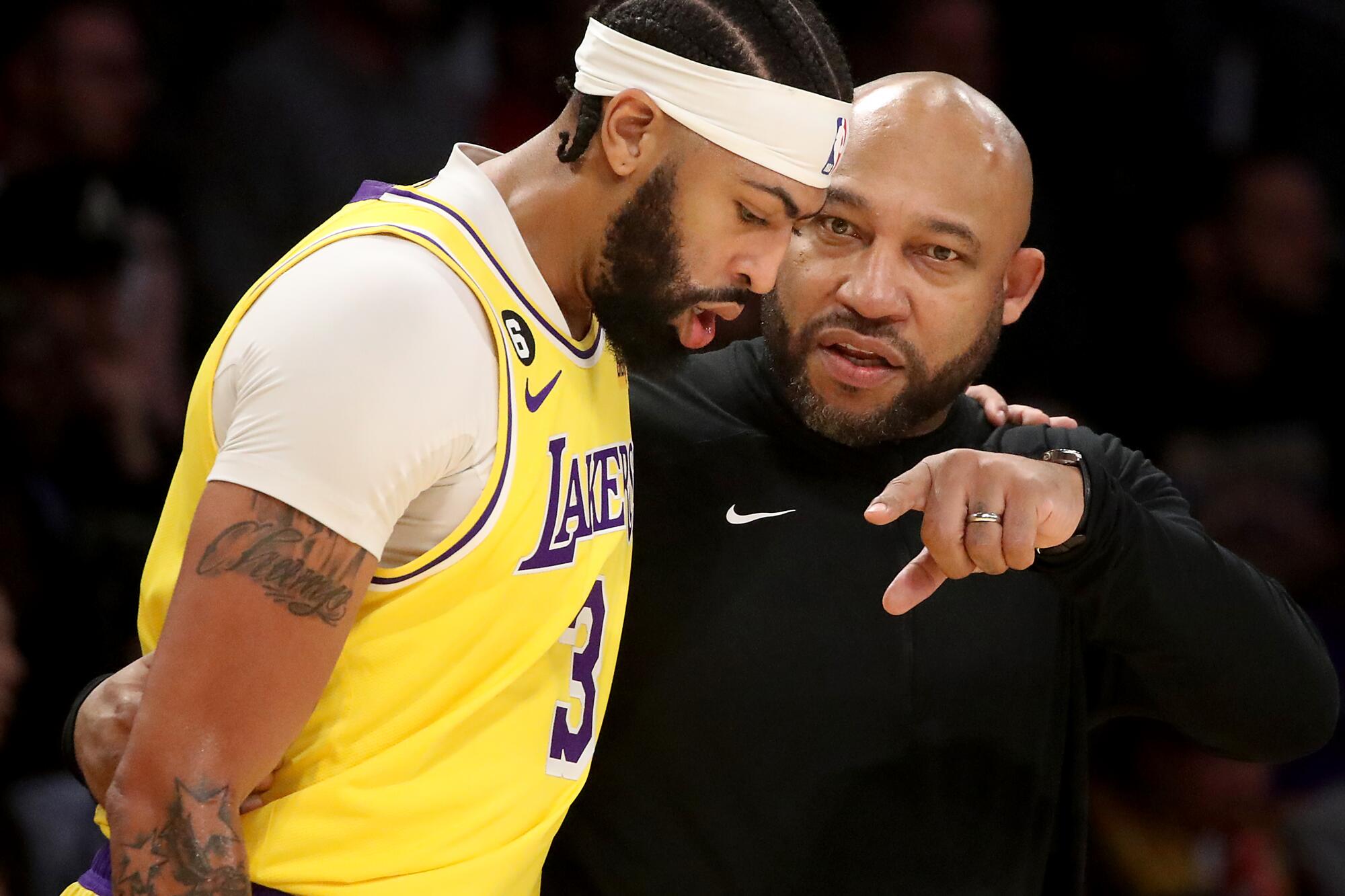 Lakers head coach Darvin Ham points toward the court as he gives instruction to forward Anthony Davis along the sideline.