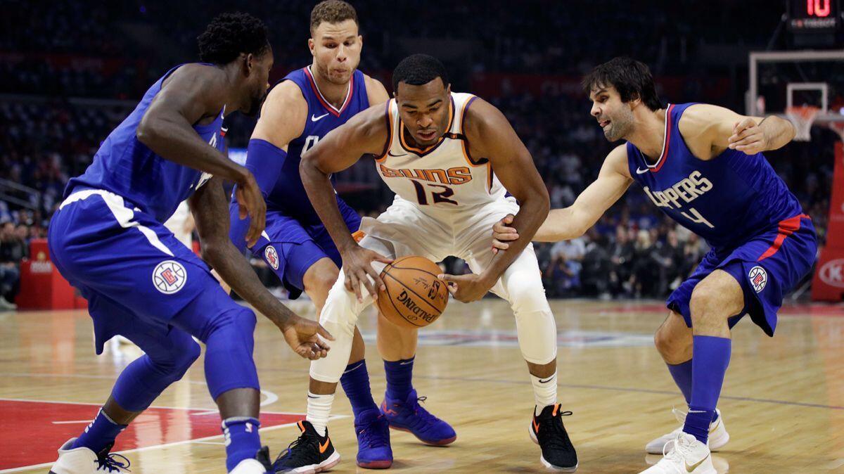 Phoenix Suns' TJ Warren, center, is defended by Clippers' Milos Teodosic, right, Blake Griffin and Patrick Beverley, left, during the first half on Oct. 21.