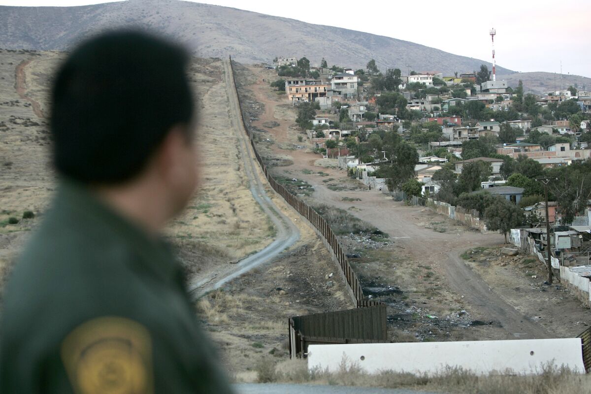 In light of the administration's focus on immigration and a border wall, school districts throughout South County are reaching out to fearful students and families. File photo shows Border Patrol agent Michael Jimenez looking at a Tijuana colonia in the shadow of Otay Mountain.