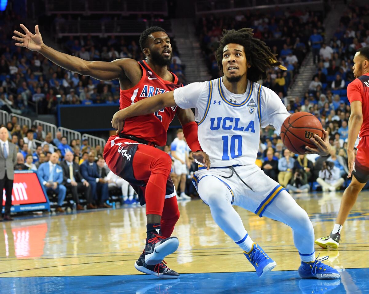 Arizona's Max Hazzard (5) guards UCLA's Tyger Campbell (10) as he drives to the basket in the first half at Pauley Pavilion on Saturday.