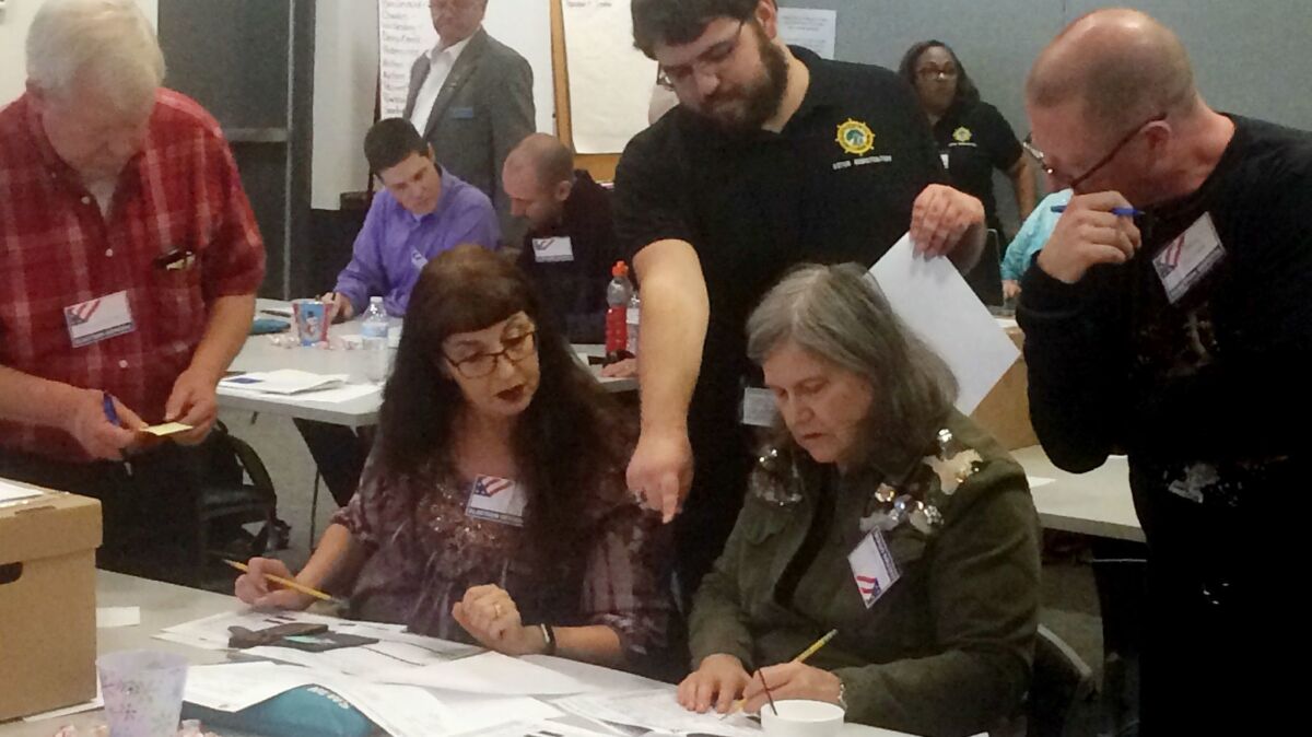 Election officials in Newport News, Va., examine ballots by hand during a recount for a House of Delegates race.