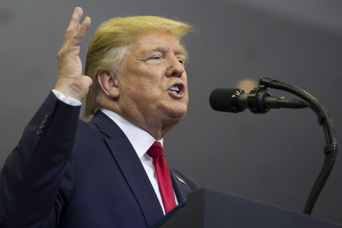 President Trump pictured from the shoulders up, gesturing as he speaks into a microphone