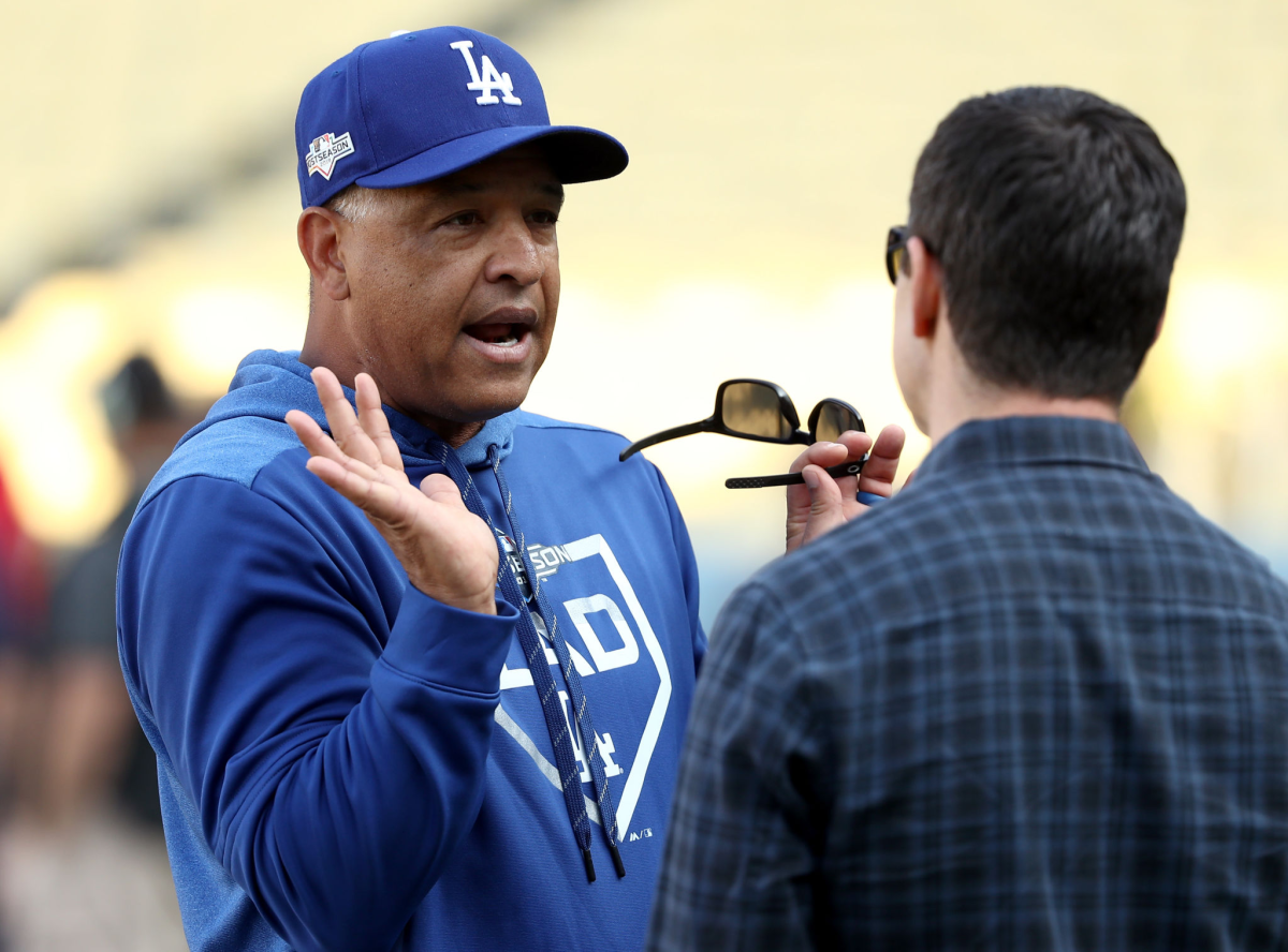Dodgers manager Dave Roberts talks to Andrew Friedman on the field.