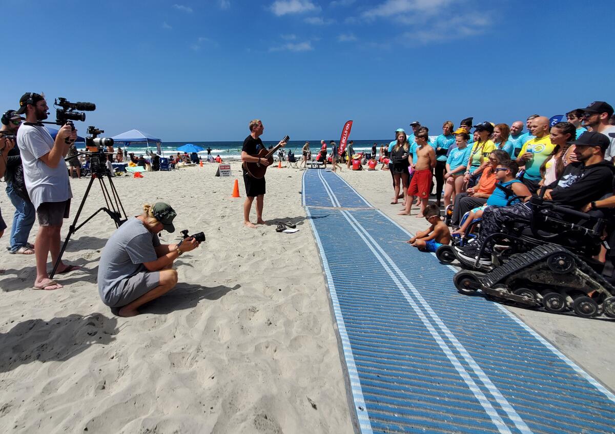 "Making Good" host Kirby Heyborne sings a song to participants in a Life Rolls On adaptive surf clinic at La Jolla Shores.