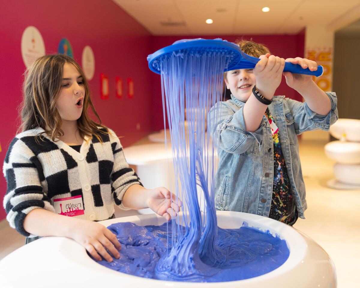 Kids stretch slime out of a vat. 