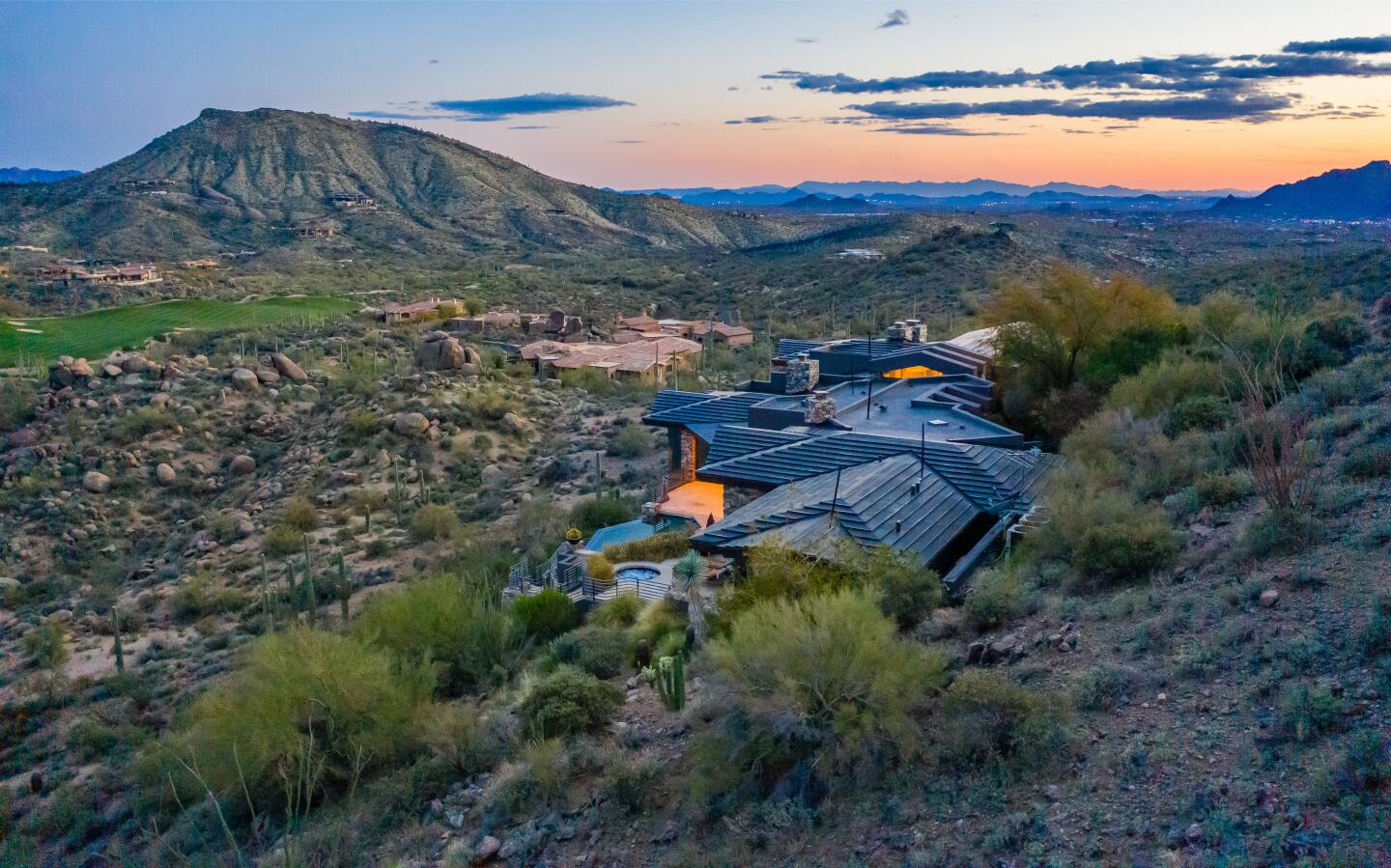 An aerial view of the top of the house and surrounding brush covered hills.