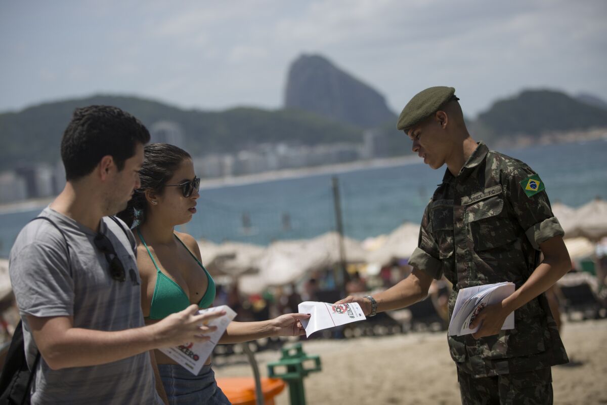 Brazilian soldier distributes pamphlets about the Aedes aegypti mosquito that spreads the Zika virus at the edge of Copacabana beach in Rio de Janeiro.