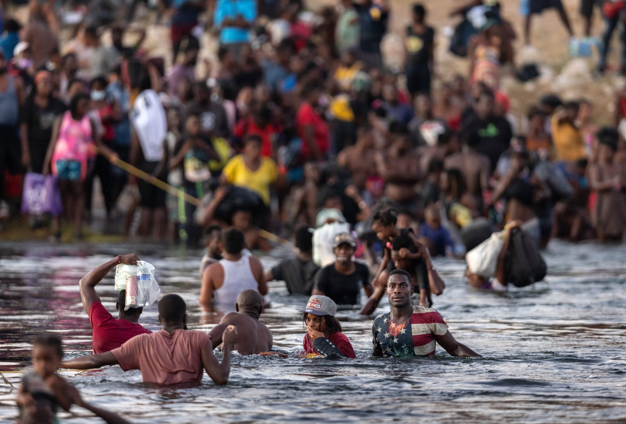 Immigrants, mostly from Haiti, gather on the banks of the Rio Grande in Ciudad Acuna, Mexico.