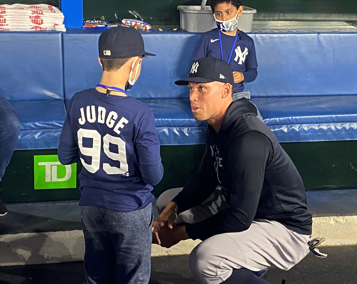 Nine-year-old Derek Rodriguez meets New York Yankees' Aaron Judge in the dugout Wednesday, May 4, 2022, before the Yankees' baseball game against the Toronto Blue Jays in Toronto. The young Yankees fan who became a viral sensation this week shed more tears of joy Wednesday when he met Judge. It came hours after cameras captured Derek tearfully hugging Blue Jays fan Mike Lanzillotta after Lanzillotta snagged Judge's sixth-inning home run ball and handed it to Derek. (Gregory Strong/The Canadian Press via AP)