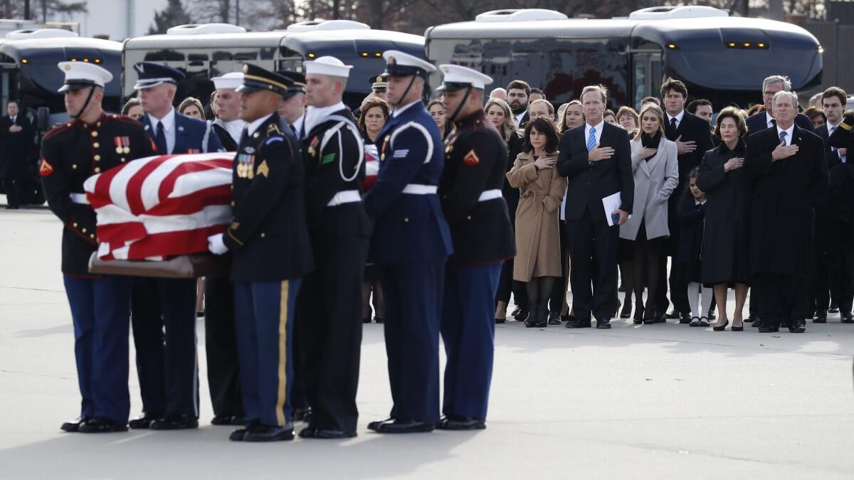 The Bush family watches as the flag-draped casket of former President George H.W. Bush is carried by a military honor guard.