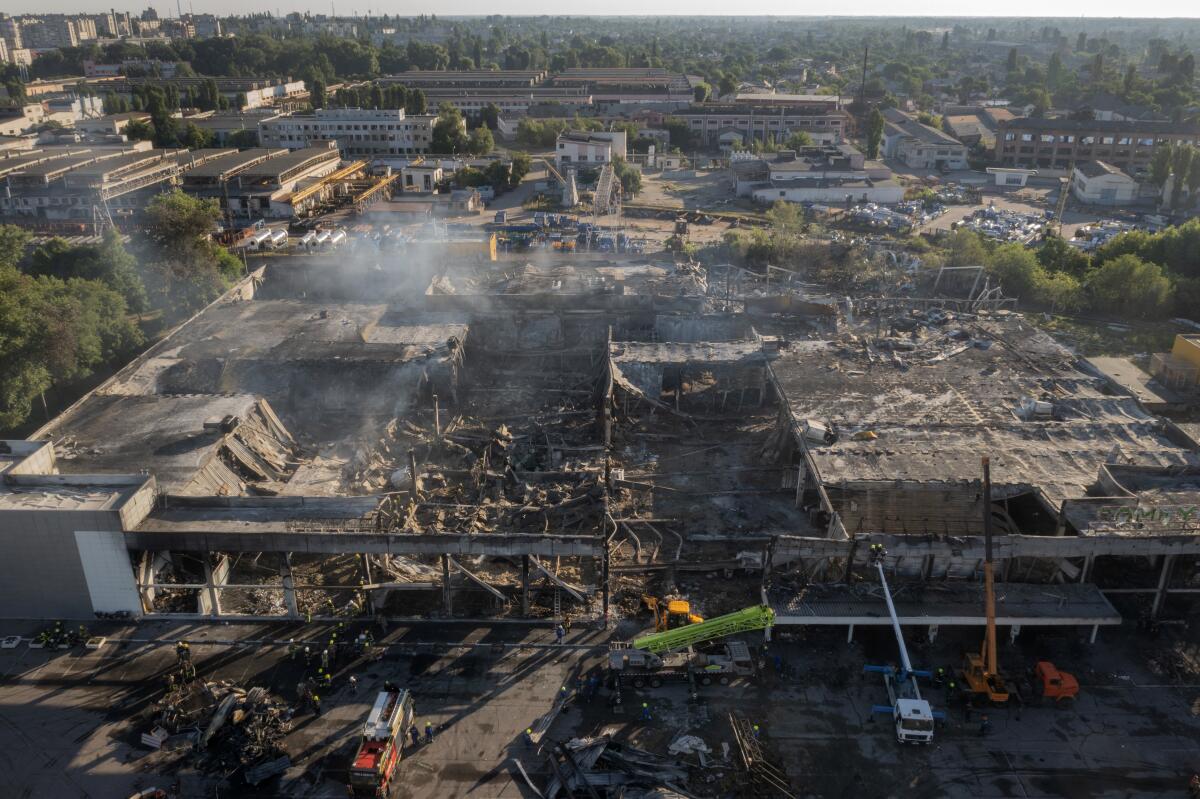 Ukrainian State Emergency Service firefighters work to take away debris at a burned shopping center.
