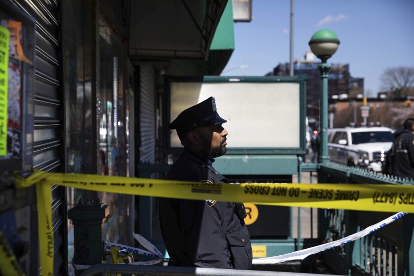 A police officer stands watch at the entrance of 36th Street Station after multiple people were shot on a subway train, Tuesday, April 12, 2022, in the Brooklyn borough of New York. (AP Photo/Kevin Hagen)