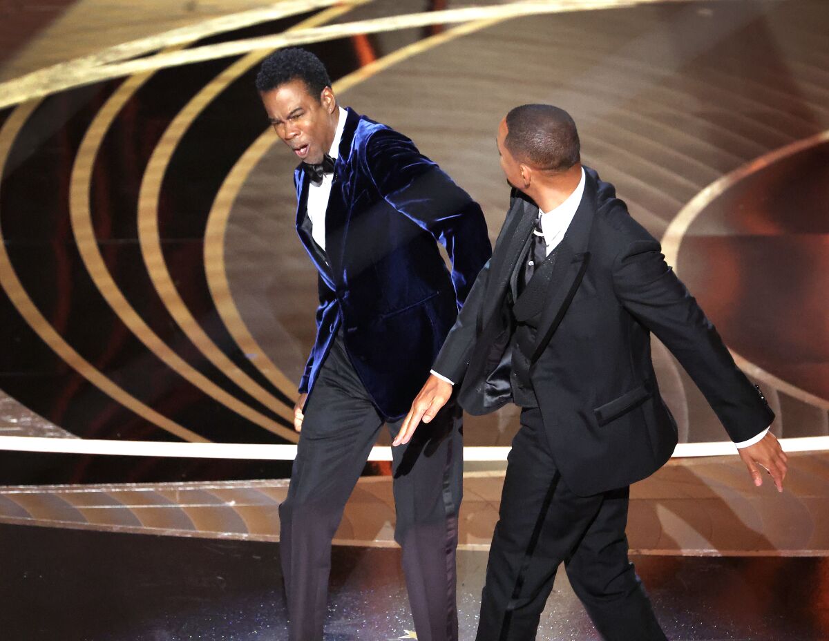 Chris Rock reels after a slap from Will Smith onstage at the 2022 Oscars.