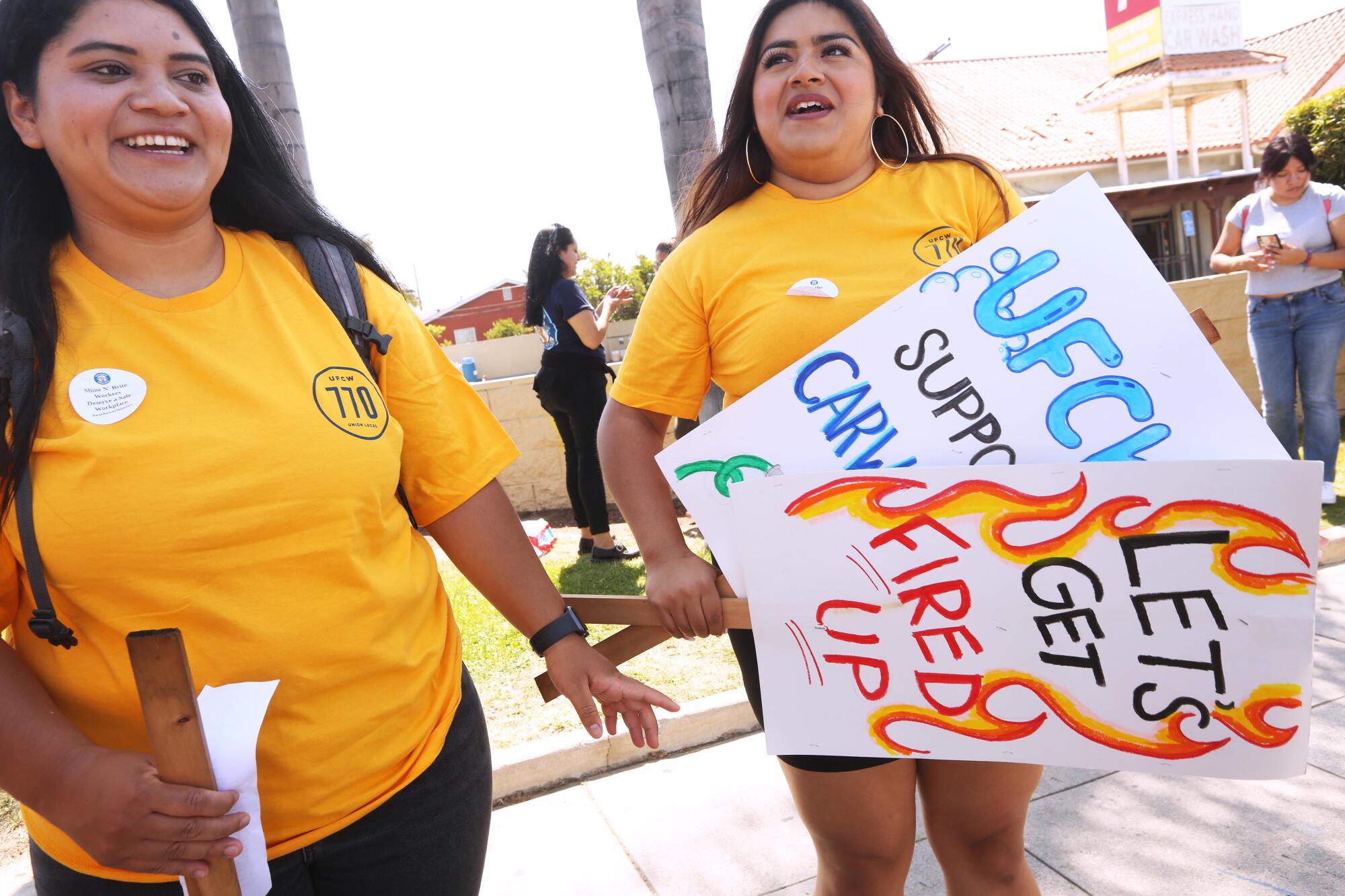 Two female UCLA students smile as they hold picket signs.