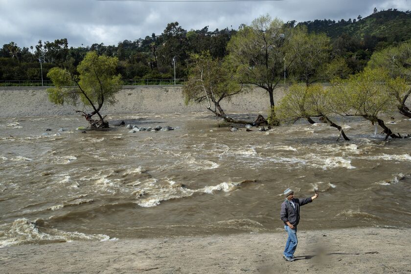 LOS ANGELES, CA-MARCH 29, 2023: David Jannesn, 49, takes a selfie next to the raging Los Angeles river near Los Feliz Blvd. In Los Angeles, during a break from the rain. (Mel Melcon / Los Angeles Times)