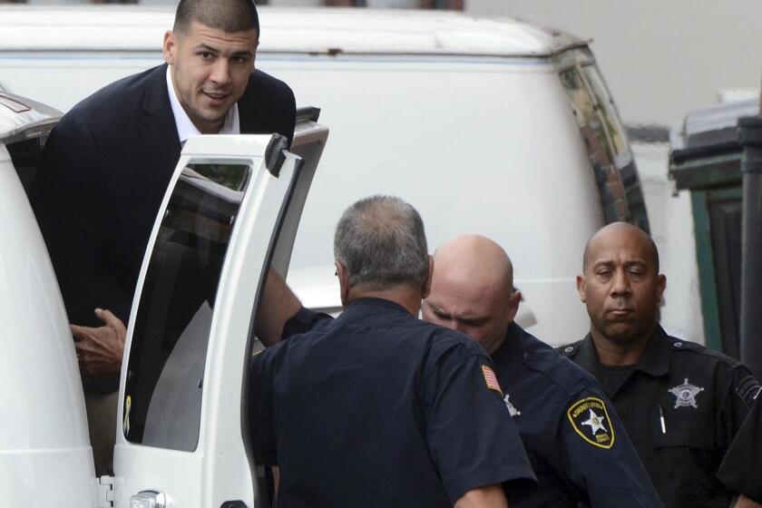 Former New England Patriots star Aaron Hernandez is escorted out of a van as he arrives for a hearing.
