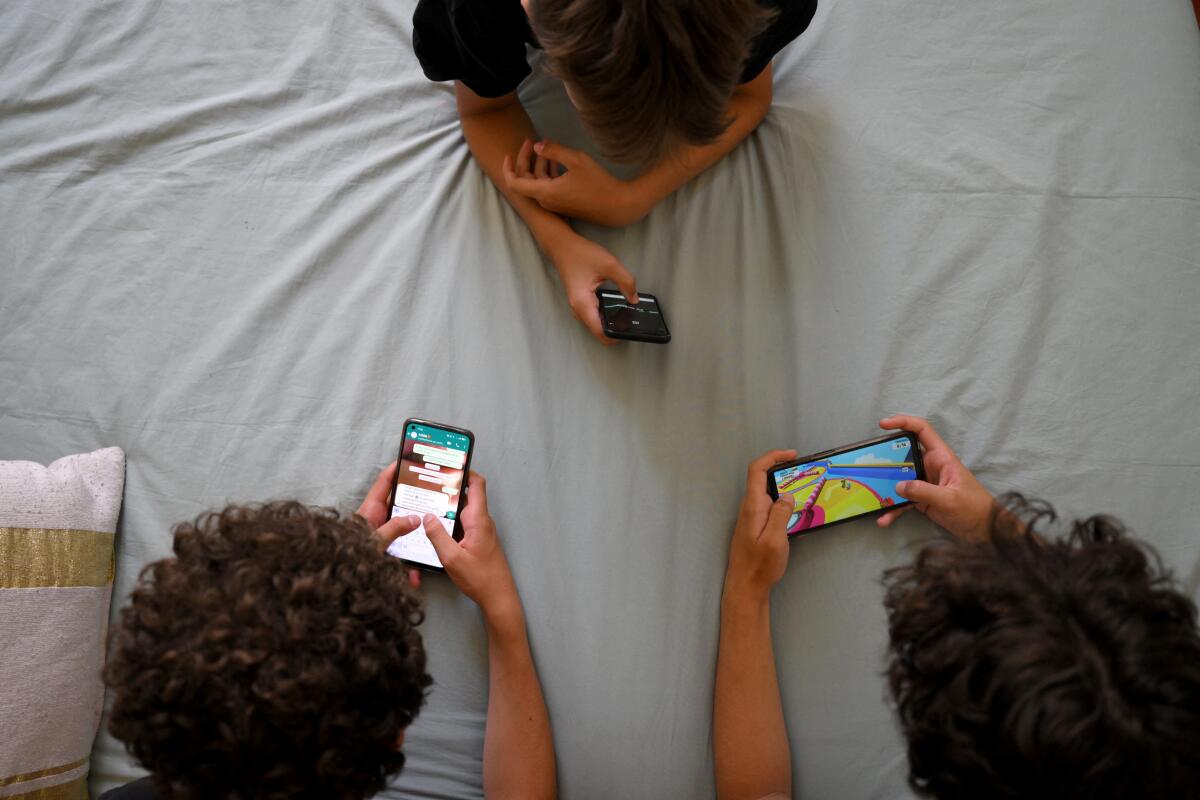 Teenagers lie down looking at phones.