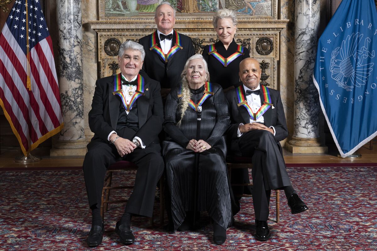 Three men and two women wear black clothing and rainbow ribbons indicating they are Kennedy Center honorees.