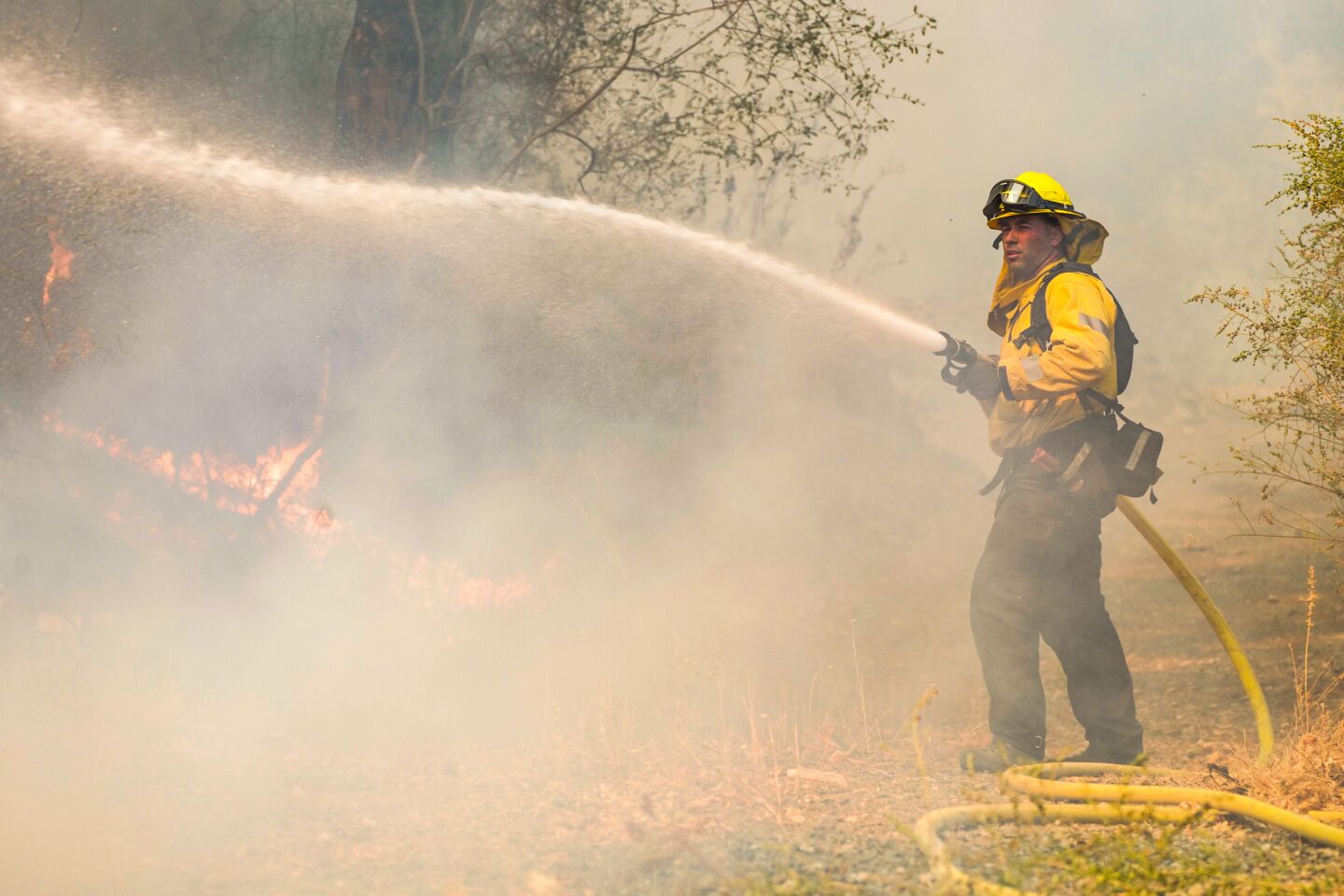A firefighter hoses down hot spots.