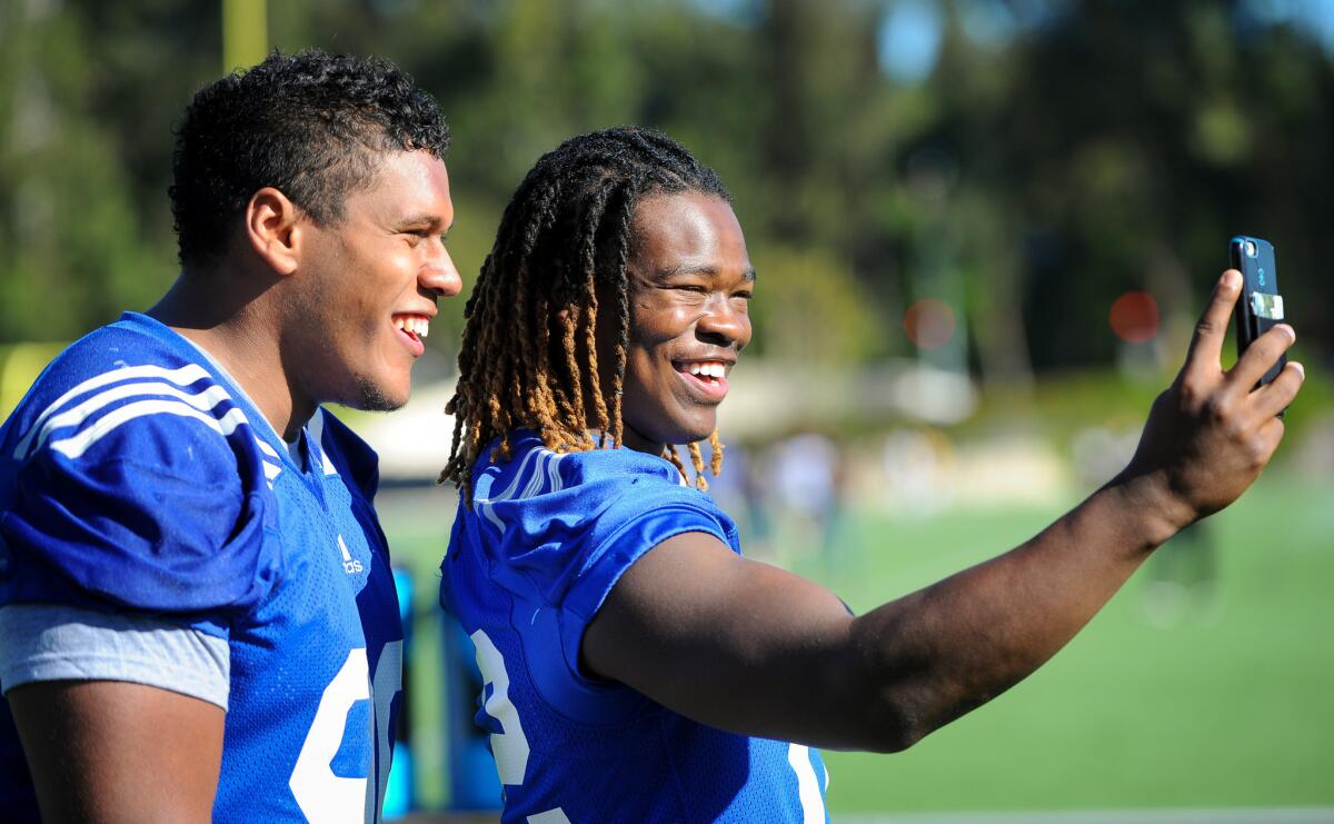 Defensive lineman Eli Ankou, left, and linebacker Jayon Brown record a video following the opening day of UCLA spring football practice.