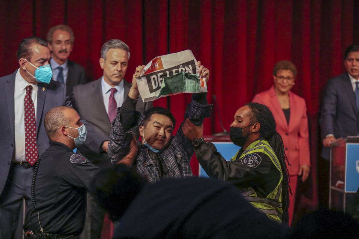 Security removes a disruptive protester holding a sign at this week's Los Angeles mayoral debate.