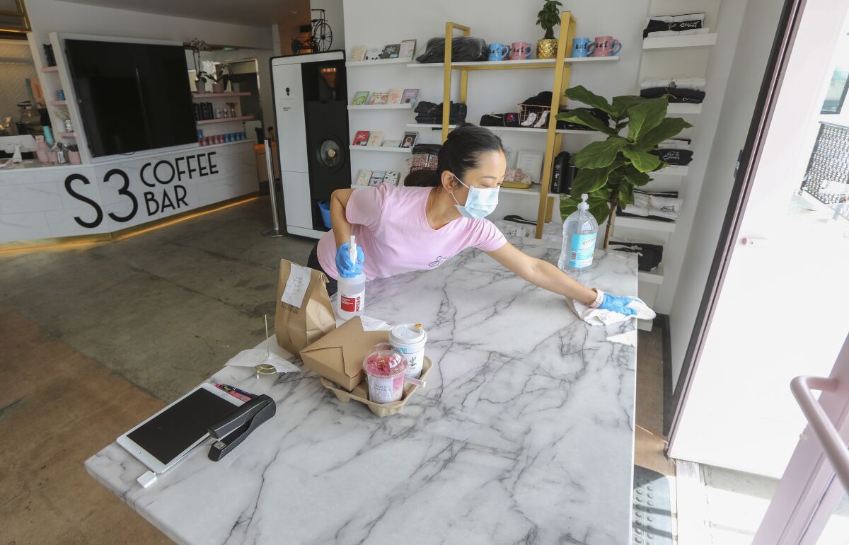 Coffee shop owner Claudia Kwong works under COVID-19 restrictions at her store called S3 Coffee Bar on Friday in San Diego. She said she will take her time reopening after the restrictions lift, ensuring her new staff has been trained appropriately to deal with the new normal way of doing business.