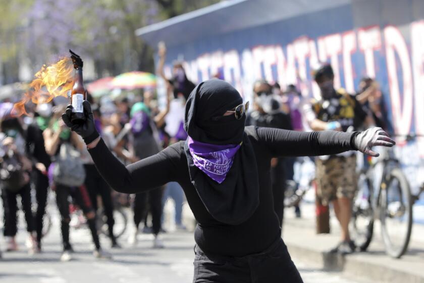 A woman gets ready to launch a petrol bomb protests during a march to commemorate International Women's Day and protest against gender violence, in Mexico City, Monday, March 8, 2021. (AP Photo/Ginnette Riquelme)