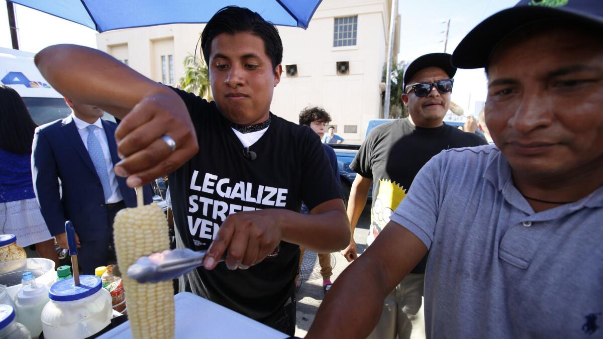 Benjamin Ramirez, left, and his father Alex Ramirez serve food from their cart during a rally in Hollywood in July 2017.