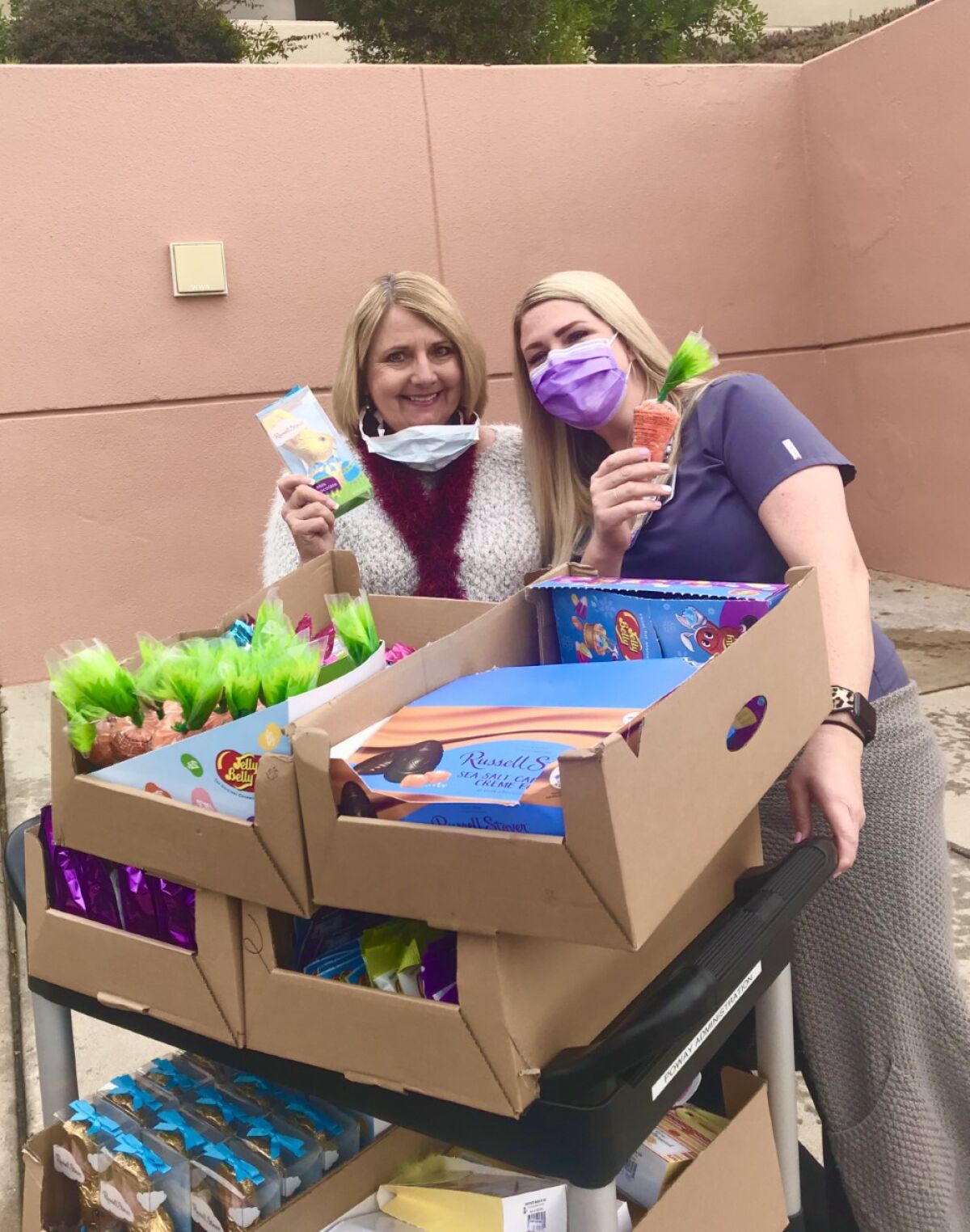 Christie Elam-Manry, left, whose family owns the nine Hallmark retail stores in San Diego County, was met at Pomerado Hospital in Poway by a hospital worker with a cart to wheel in all the Easter candy which was on the shelves of Hallmark stores when they closed. The Elams donated about $12,000 worth of candy to area hospitals.