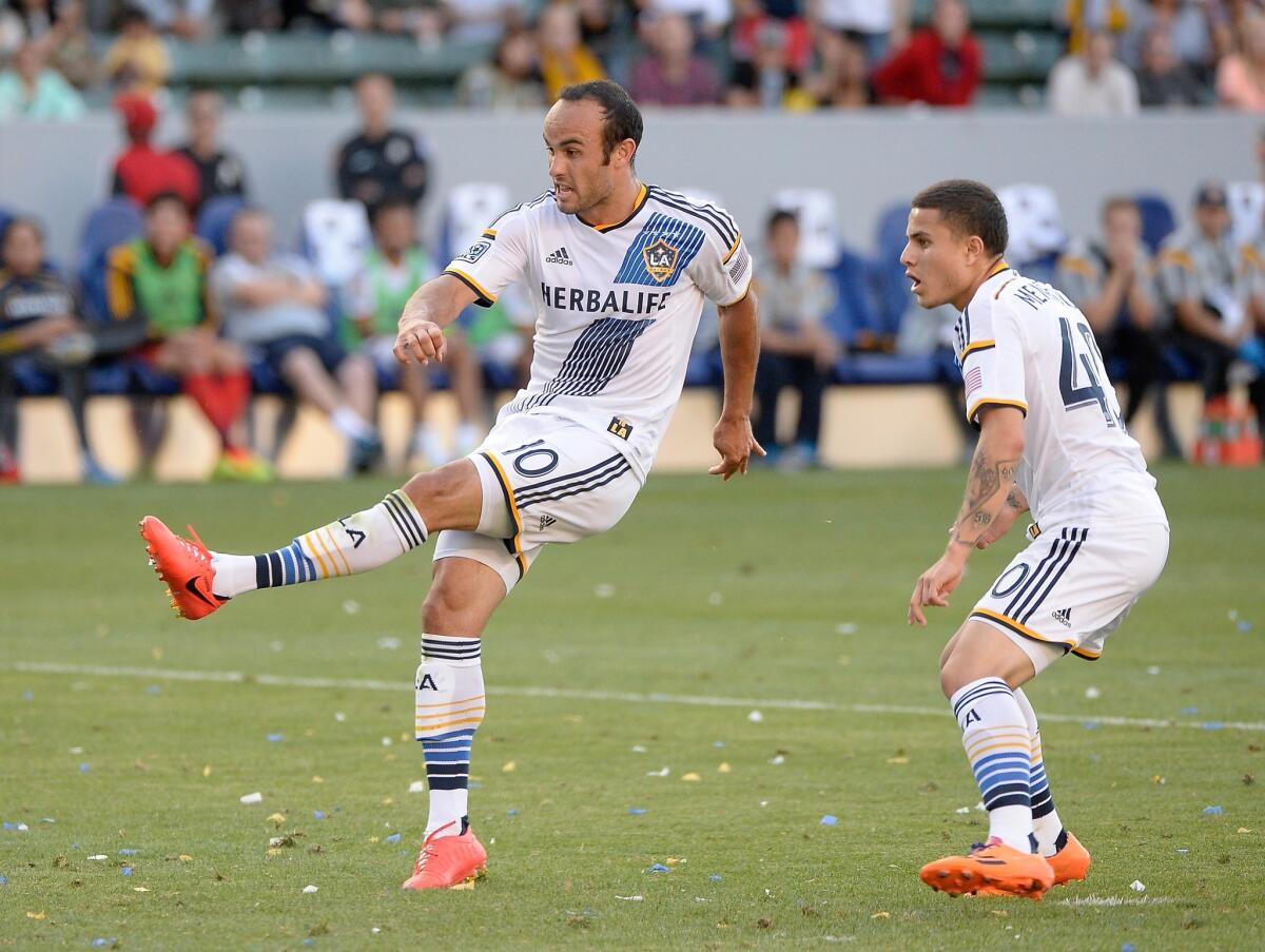 Landon Donovan, left, watches a goal with Raul Mendiola, right, during a match May 25.