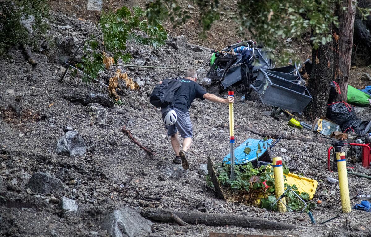 Homeowner Olin Richie trys to hike up to his house through mud and debris in Forest Falls.