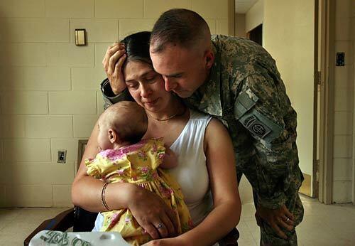 In the hours before their 15-month separation, Capt. Kevin Agness and his wife, Chiara, share a moment with their baby, Gabriella, in his Ft. Bragg office.