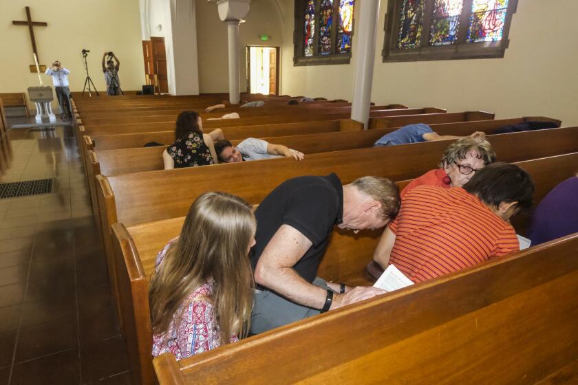 South Pasadena, CA - October 15: Church goers take protective actions in the pews at St James Episcopal Church during an earthquake drill after the conclusion of the Sunday service on Sunday, Oct. 15, 2023 in South Pasadena, CA. In conjunction with the Great ShakeOut, seismologist Dr. Lucy Jones led an earthquake drill at St. James Episcopal Church in South Pasadena to demonstrate an essential post-disaster communication process developed in conjunction with the Episcopal Diocese of Los Angeles. (Ringo Chiu / For The Los Angeles Times)