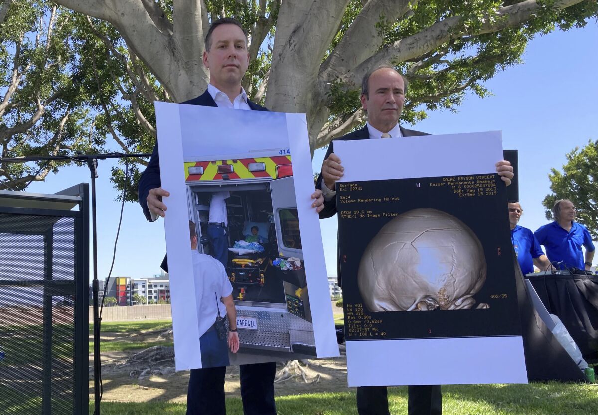 Attorney Keith Bruno, left, and Kyle Scott, representing the Galaz family, hold up a photo of Bryson Galaz and imaging of his skull during a press conference in Anaheim, Calif. on Thursday, April 7, 2022. The mother of Bryson Galaz, who was accidentally hit in the head with a baseball thrown by a Los Angeles Angels pitcher warming up before a game, has filed a lawsuit against the team. Beatrice Galaz says in the lawsuit announced Thursday that the team's negligence led to the traumatic brain injury suffered by her then-6-year-old son at Angel Stadium in September 2019. (AP Photo/Amy Taxin)