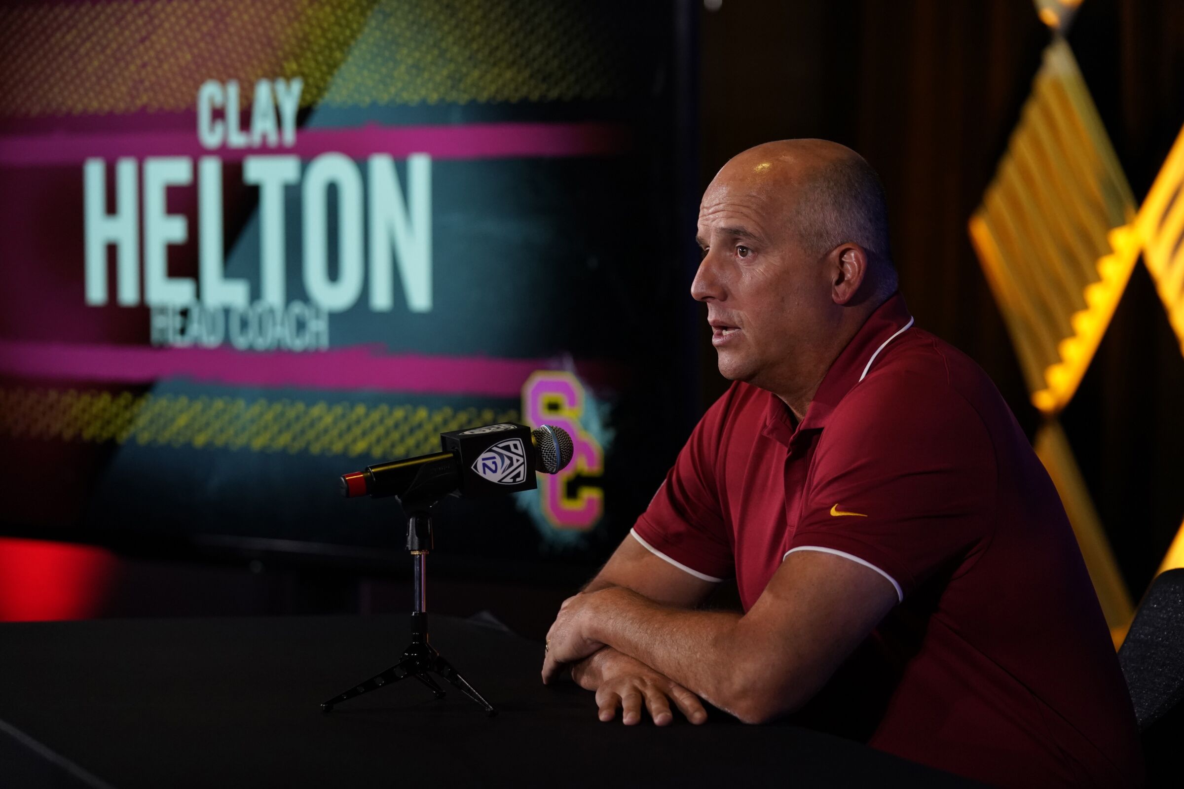  USC coach Clay Helton sits and speaks into a microphone during Pac-12 media day.