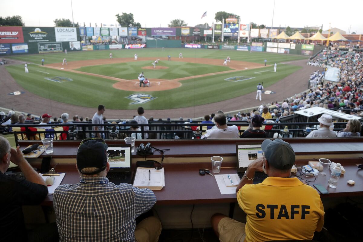 FILE - In this July 10, 2019, file photo, Ron Besaw, right, operates a laptop computer as home plate umpire Brian deBrauwere gets signals from radar with the ball and strikes calls during the fourth inning of the Atlantic League All-Star minor league baseball game in York, Pa. The Atlantic League announced Thursday, Jan. 13, 2022, it is restoring its pitching mound to 60 feet, 6 inches from home plate and returning strike zone judgement to umpires after experimenting with moving the rubber back a foot and using an automatic ball-strike system. (AP Photo/Julio Cortez, File)