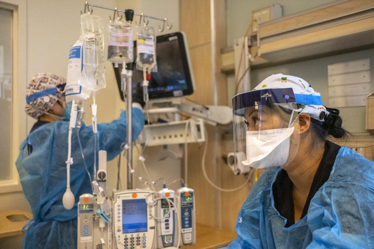 Hospital workers wear masks and gowns.