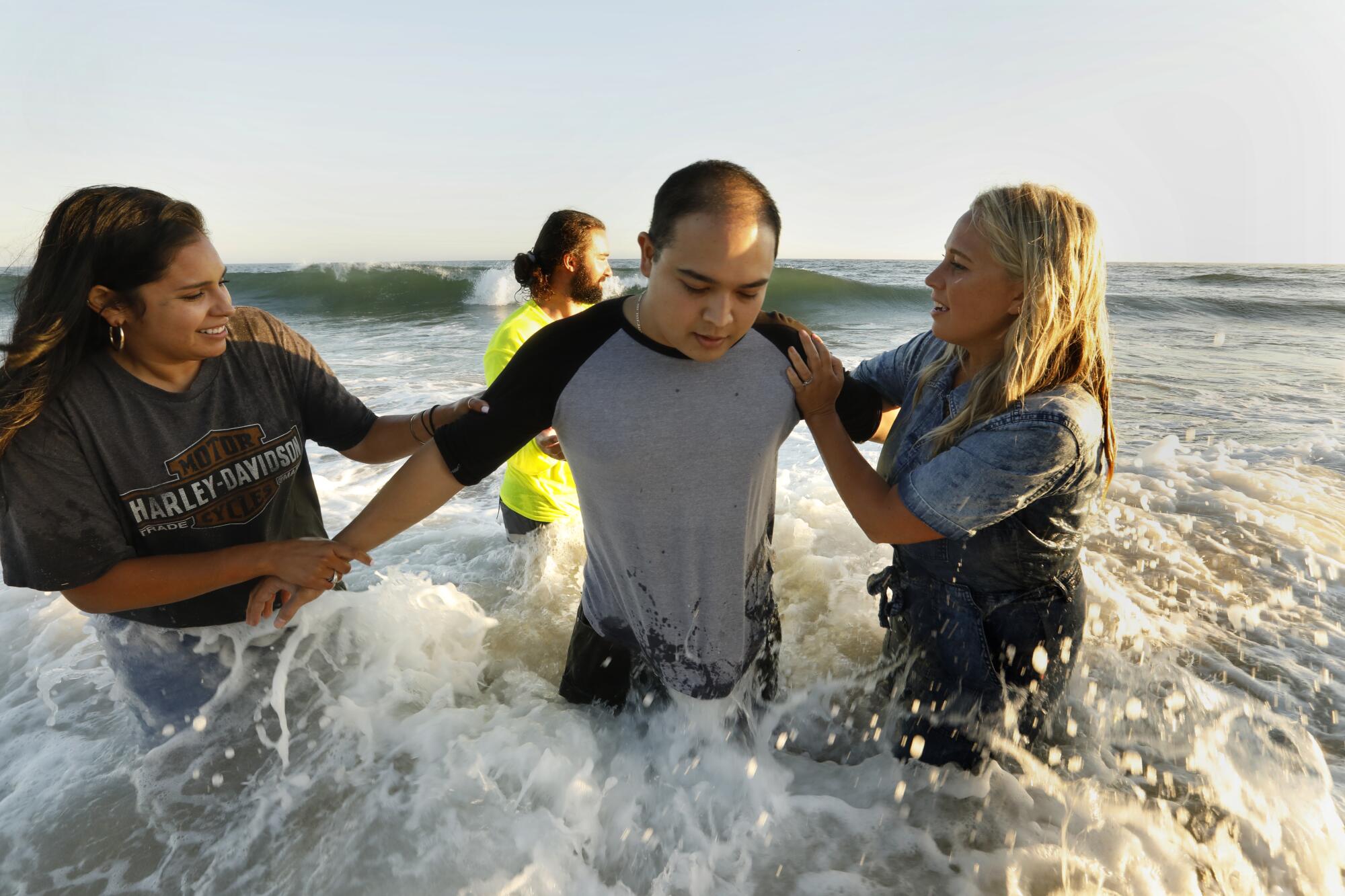 A man is baptized at Newport Beach by members of Saturate OC.