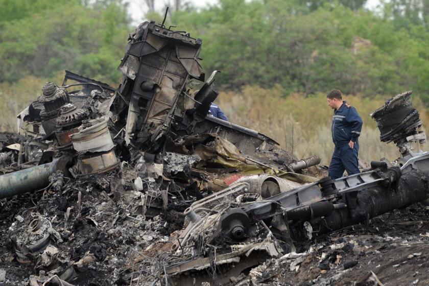 Rescuers stand on July 18 at the site of the crash of a Malaysia Airlines jet near the town of Shaktarsk in eastern Ukraine.