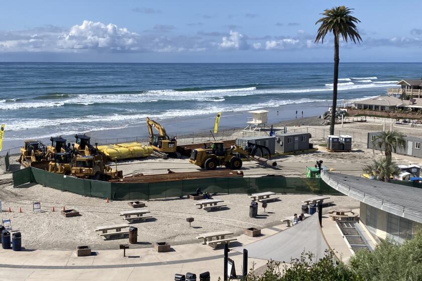 A crew from Manson Construction assembles equipment Thursday at Moonlight Beach to begin sand replenishment in Encinitas.