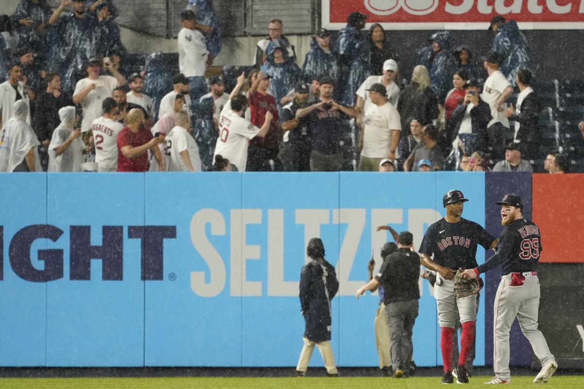 Boston Red Sox first base coach Tom Goodwin, second from left, calms left fielder Alex Verdugo (99) after he was hit in the back by an object thrown by a fan during the sixth inning of a baseball game against the New York Yankees, Saturday, July 17, 2021, in New York. (AP Photo/Mary Altaffer)