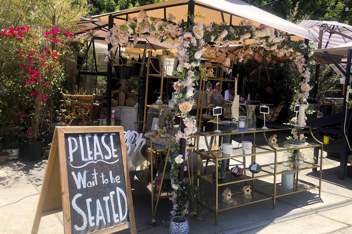 Outdoor dining with a sign that says, "Please wait to be seated"