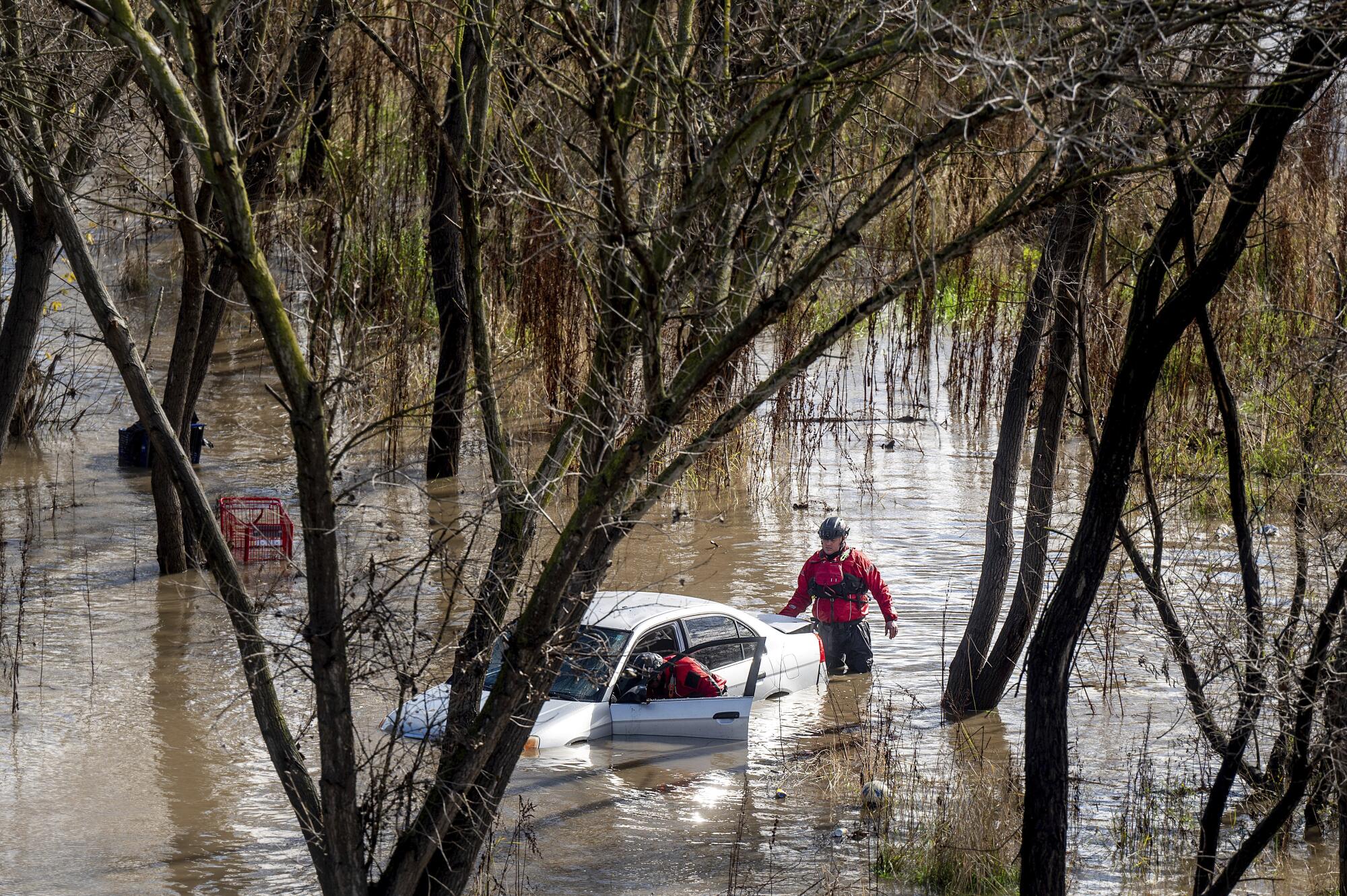 Search and rescue workers investigate a car surrounded by floodwater as heavy rains caused the Guadalupe River to swell.